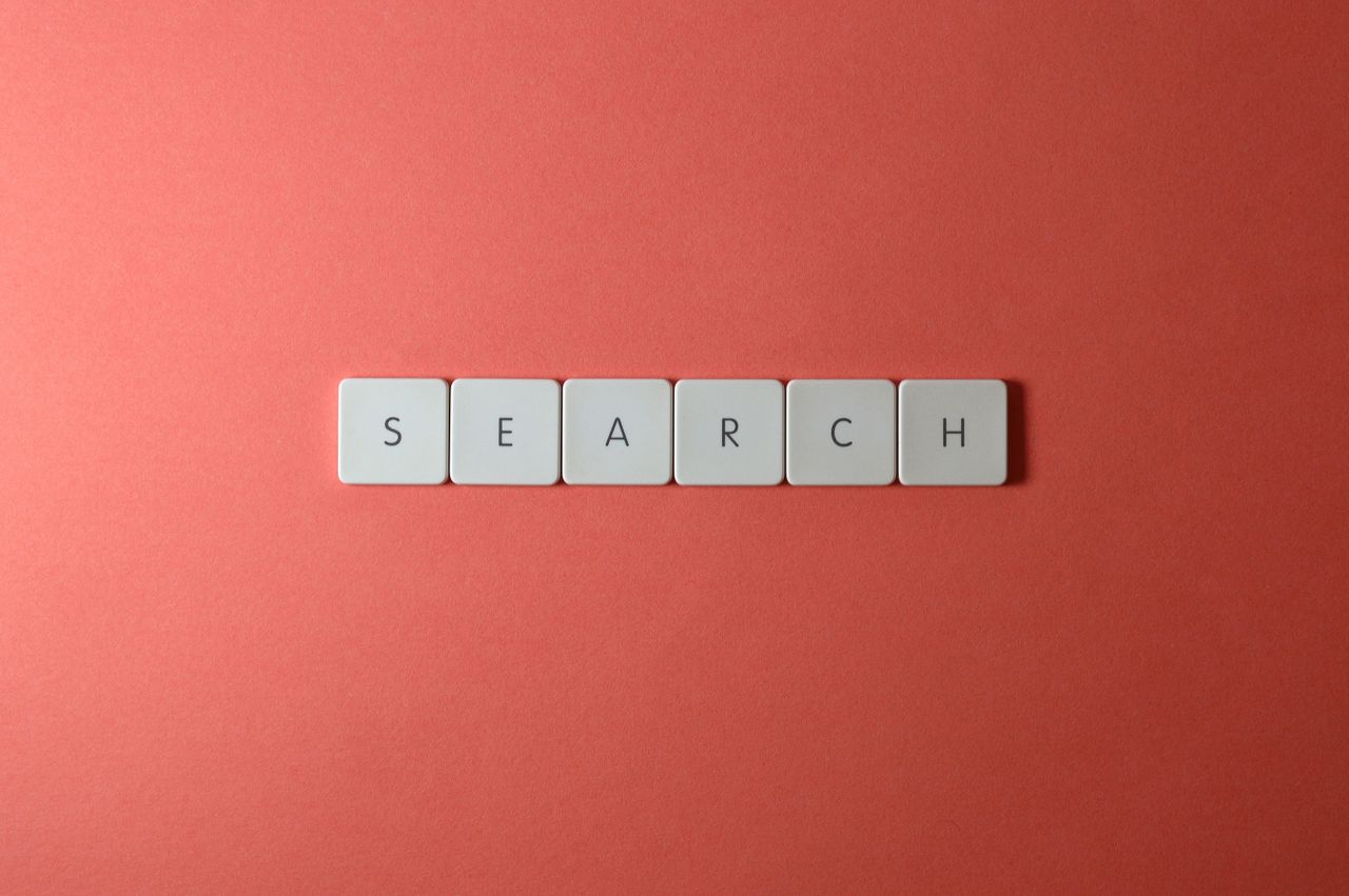 about-002 White keyboard keys spelling search on a bold red surface, conceptual design with copyspace.